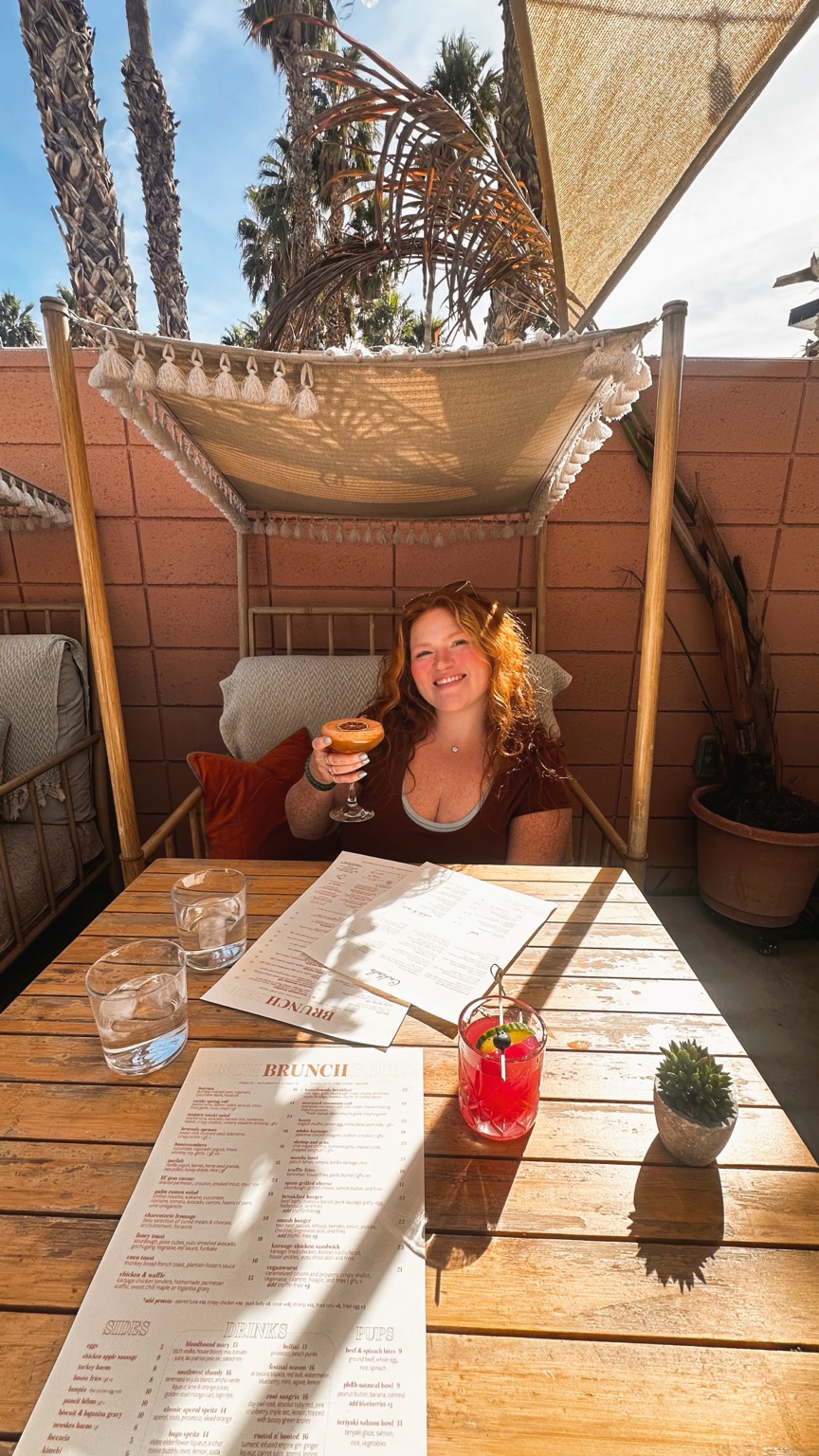 Kayti raising a glass beneath a tasseled cabana